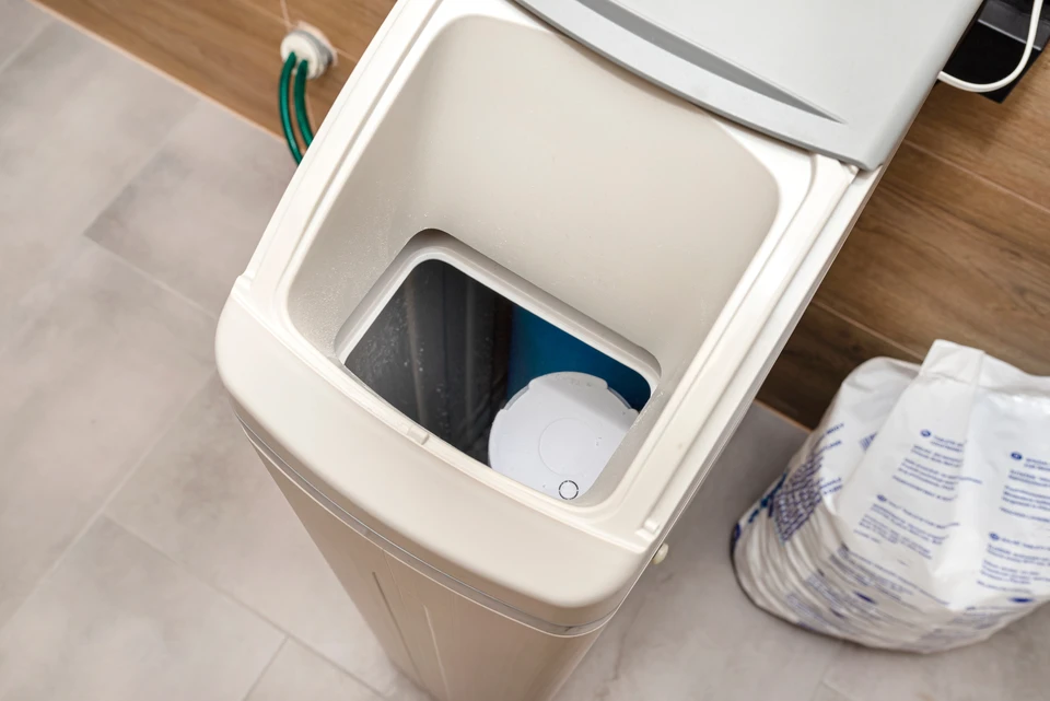 Technicien en combinaison bleue installant un système de filtration d'eau sous évier de cuisine moderne